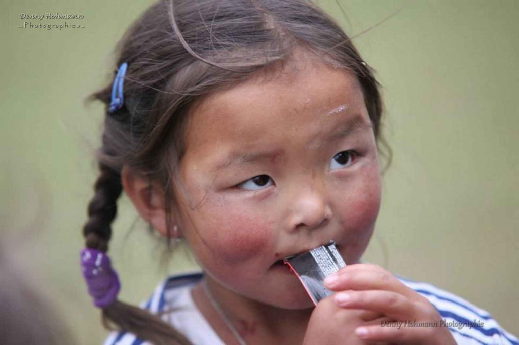 Portrait rapproché d'une jeune fille mongole en train de manger du chocolat