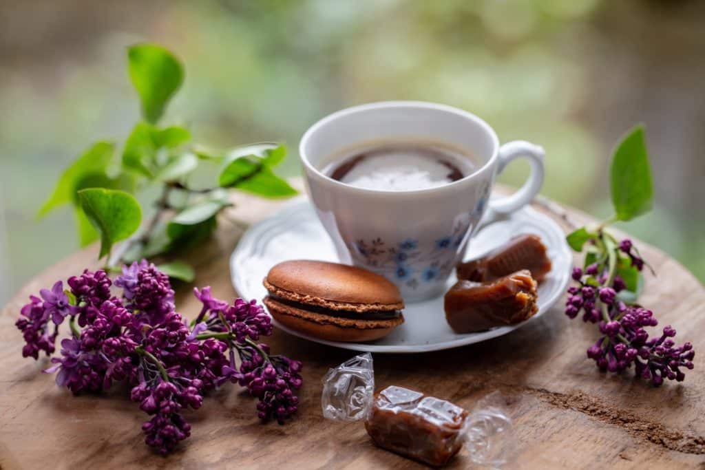 Tasse de café avec macaron au caramel et fleurs de lila