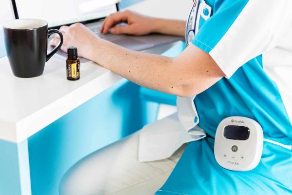 Photo médicale d'une infirmière en train de rédiger un rapport, le tire-lait Ameda Joy accroché à la poche